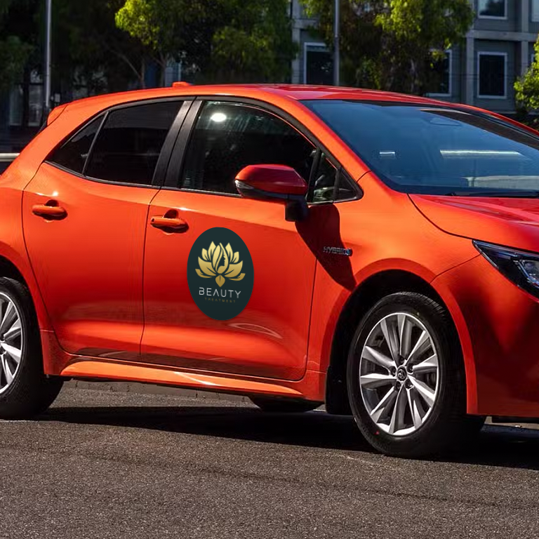 An orange car with a 'Beauty' brand magnetic sign on the drivers side door.