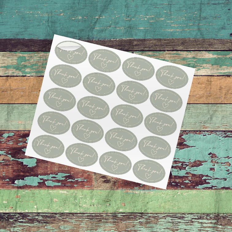 A set of custom oval-shaped stickers with a design, placed on a wooden background. The stickers have a glossy finish and are intended for labeling or personal use.