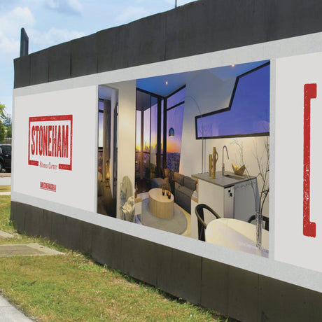 A large rectangular vinyl banner featuring a printed image of a modern living room with a view of a sunset through the window, and the text 'STONEHAM' and 'Modern Living Spaces' below it.